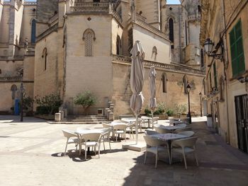 Empty chairs and tables by buildings in city