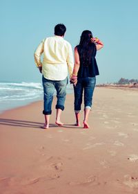 Rear view of friends walking on beach