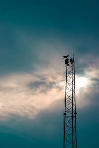 Low angle view of communications tower against sky during sunset