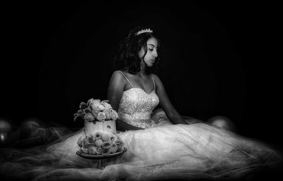 Portrait of woman sitting against black background