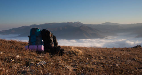 Backpacks on mountain against cloudscape