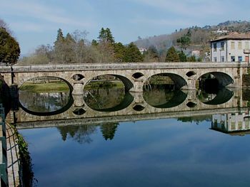 Arch bridge over river against sky