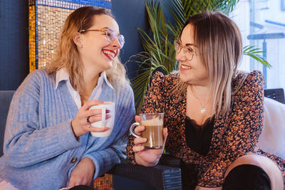 Young women talking while holding coffee