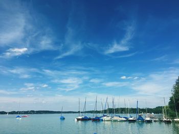 Sailboats moored in sea against sky