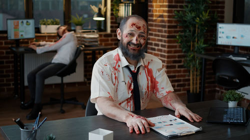 Portrait of senior man sitting on table