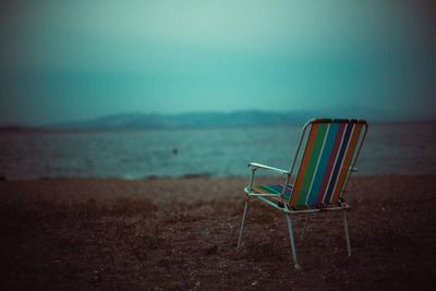 Empty chairs on beach against sky