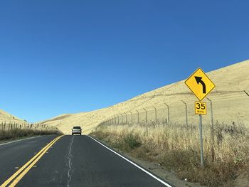 Road sign against clear blue sky