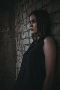 Portrait of young woman standing against wall