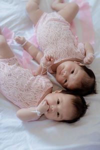 High angle portrait of baby girl lying on bed at home