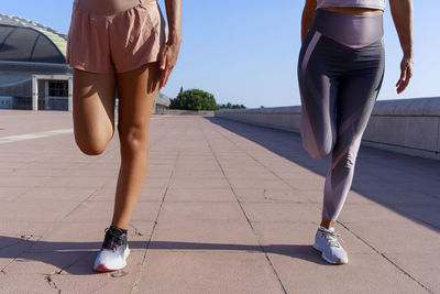 Mother and daughter stretching legs on sunny day