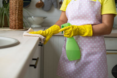 Midsection of woman holding umbrella at home