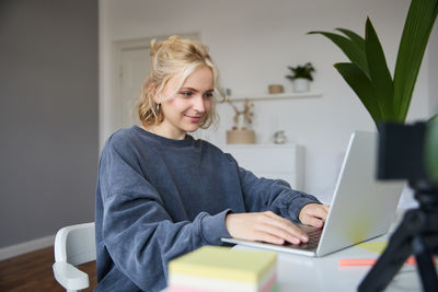 Portrait of young woman using laptop at home