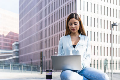Businesswoman using laptop sitting outdoors