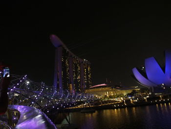 Illuminated city by river at night