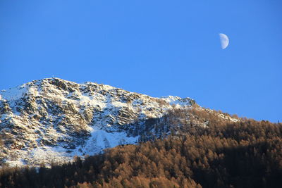 Low angle view of snowcapped mountain against clear blue sky