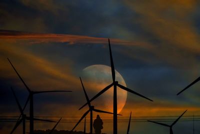 Low angle view of silhouette windmills against sky during sunset