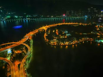 Illuminated bridge over river in city at night