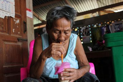 Mid adult woman holding drink while sitting outdoors