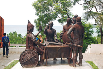 Rear view of people by statue against clear sky