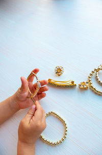 Childrens hands play with gold jewelry and bijouterie, on white background. 