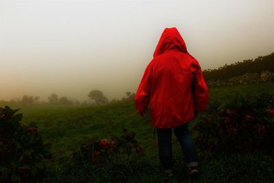 Woman with red umbrella against trees during sunset