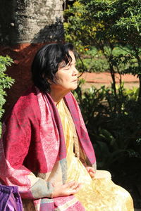 Senior woman with closed eyes meditating by plants at park