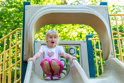 Little happy child on a slide on a playground in the park on a sunny summer day
