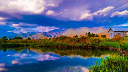 Scenic view of lake by houses against sky