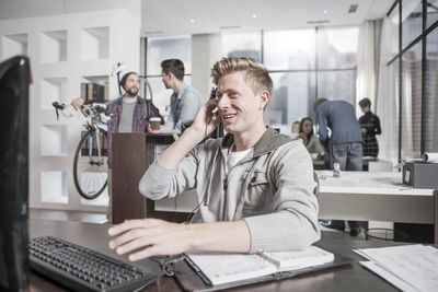 Young man at desk in office wearing a headset