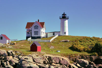 Lighthouse amidst rocks and buildings against sky