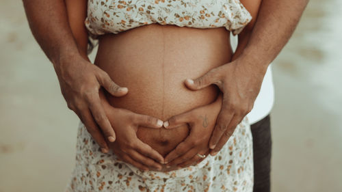 Midsection of man touching woman standing against wall