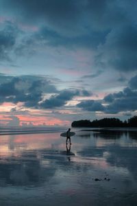 Silhouette surfer boy walking with surf board  in sunset time