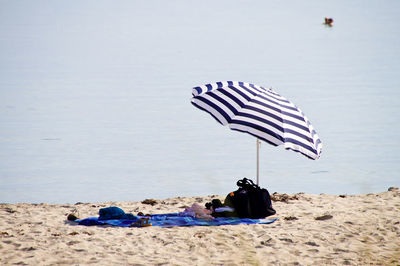 Deck chairs on rocks at beach against sky