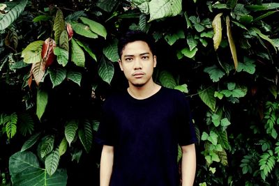 Portrait of young man standing in forest