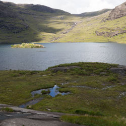 Scenic view of lake by mountains against sky