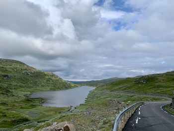 Scenic view of road by mountains against sky