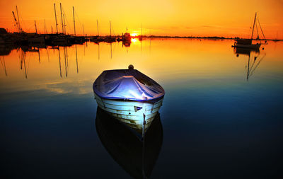 Boats moored in marina at sunset