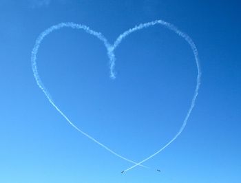 Low angle view of heart shape vapor trail in sky