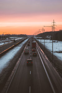 Cars on road against sky during sunset