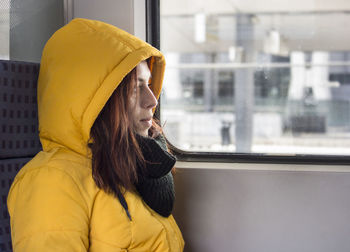 Side view of young woman looking through window