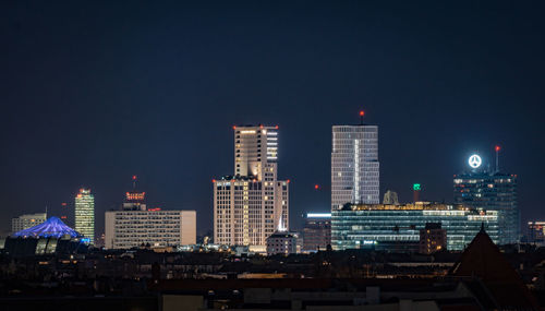 Illuminated buildings in city against sky at night