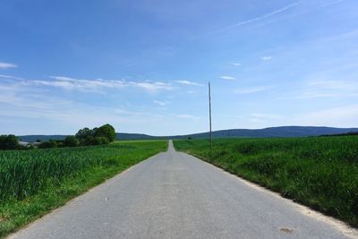 Road amidst field against sky