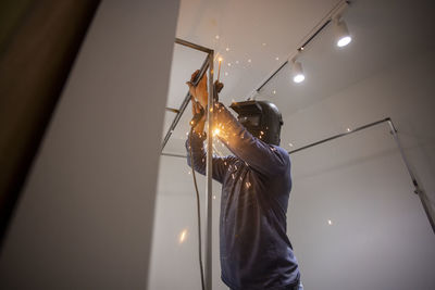 Low angle view of woman working on ceiling