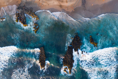 Aerial view of waves splashing on rocks at beach