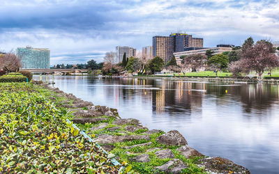 Scenic view of river by buildings against sky