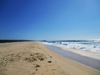 Scenic view of beach against clear blue sky