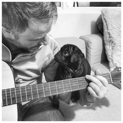 Man playing guitar with dog at home