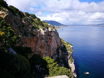 Scenic view of cliff by sea against sky