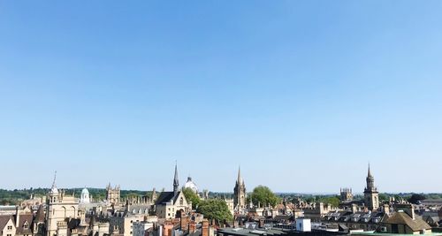 Panoramic view of buildings in city against clear blue sky