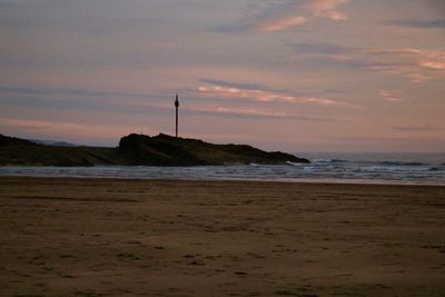 Scenic view of beach against sky at sunset